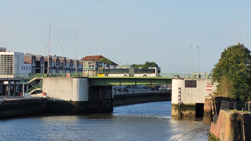 Ein Bus fährt über eine Brücke, die über einen Fluss führt.