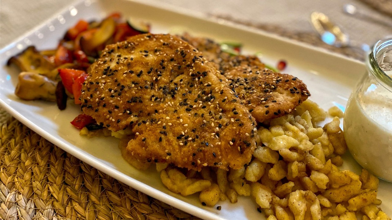 Ein Teller mit einem panierten Schnitzel mit Sesam