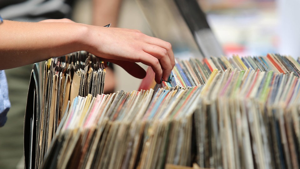 Person durchsucht einen Stapel Schallplatten